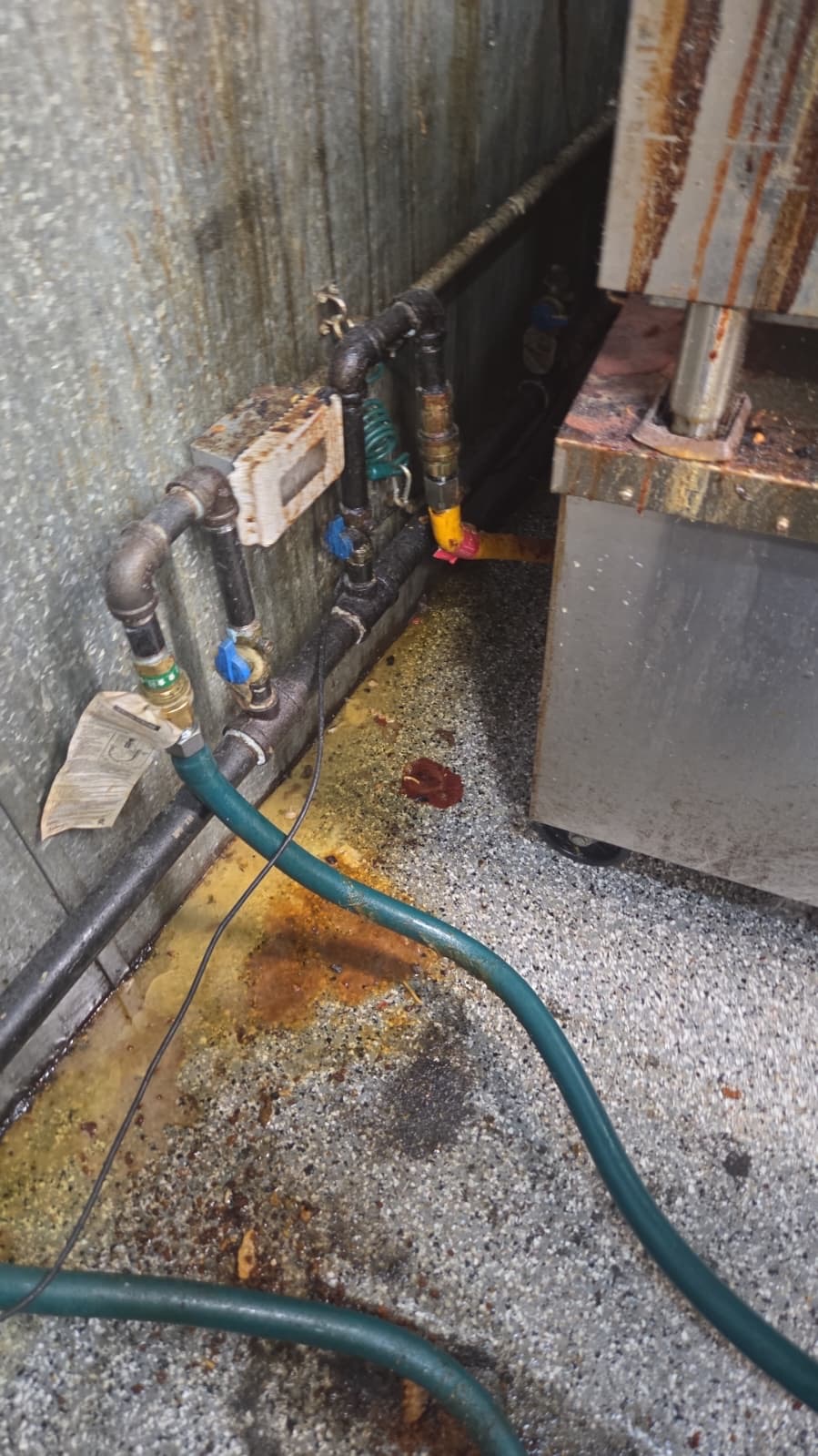 Greasy and rusted commercial kitchen pipe run before cleaning